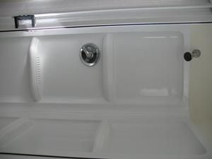 Empty white refrigerator interior with compartments, a light, and a door latch.