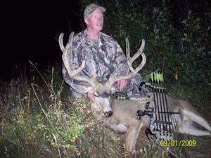Man in camouflage with large buck and bow. September 2009.