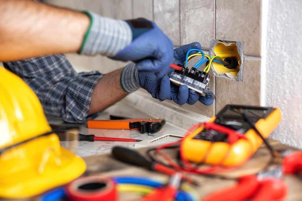 An electrician is working on an electrical outlet