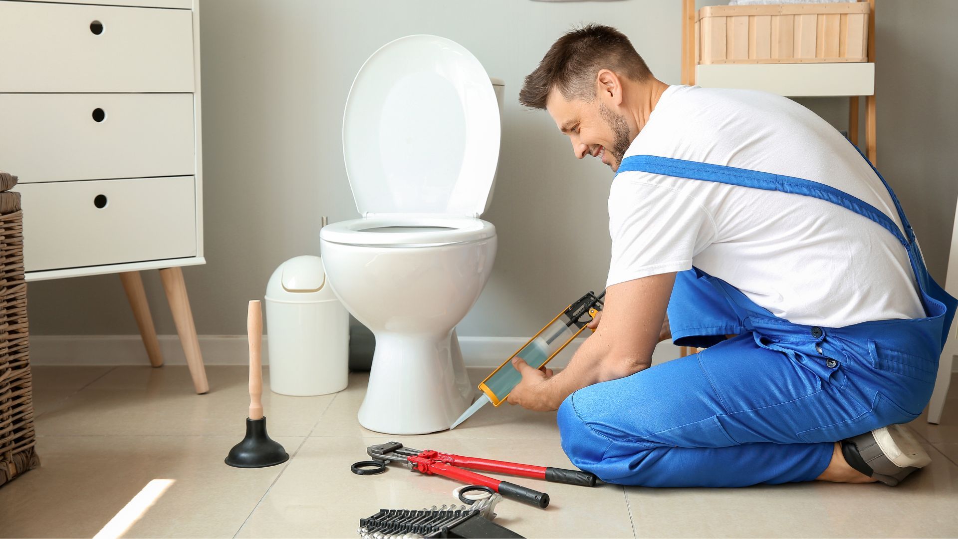 A man is fixing a water heater in a bathroom.