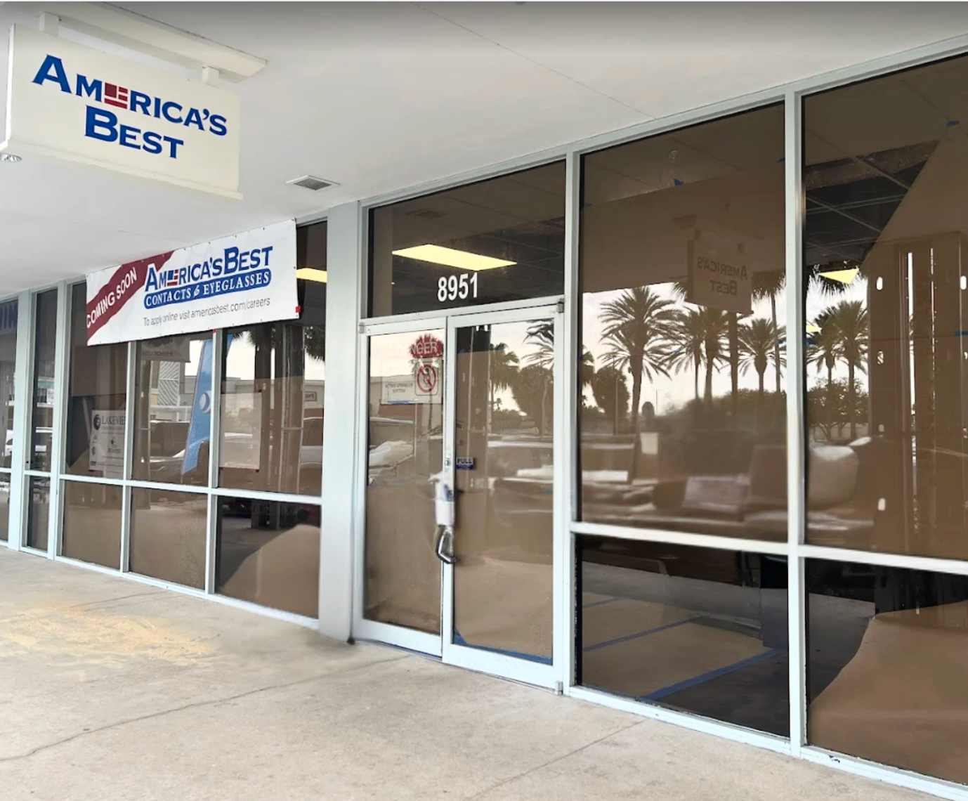 Storefront of America's Best, brown-tinted windows, white trim. Number 1351 above the door. Banner over entrance.