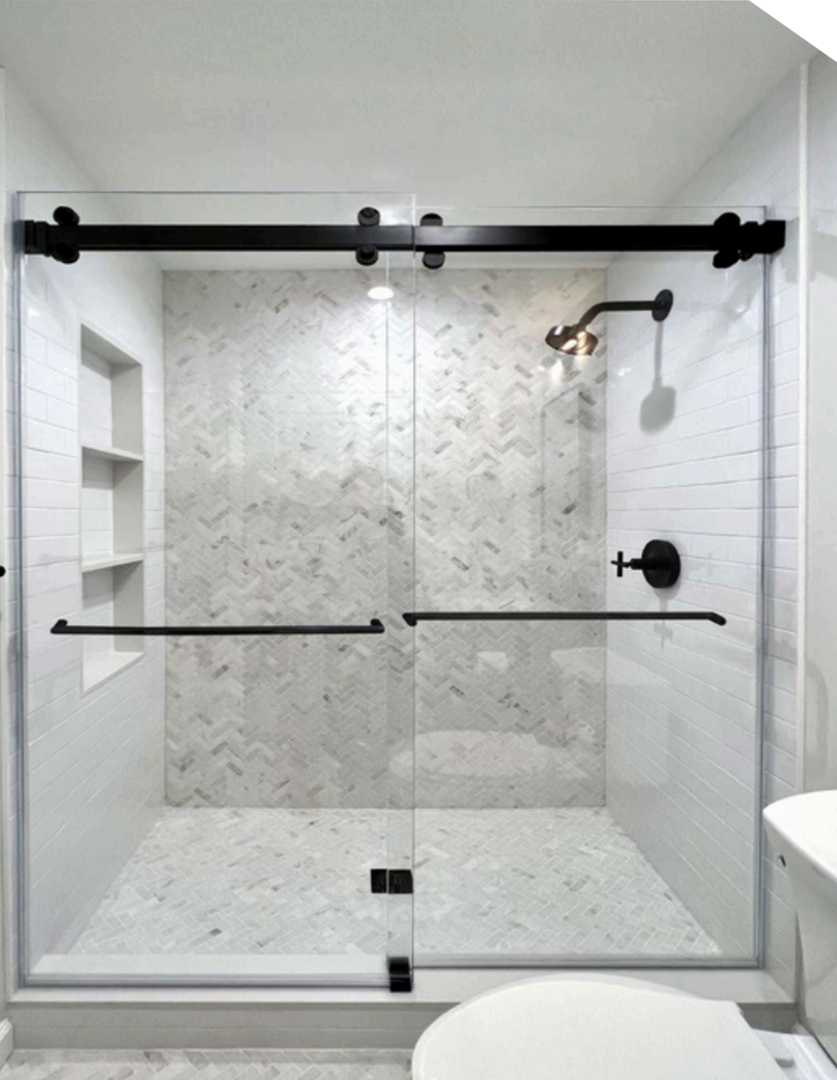 Modern shower with sliding glass doors, black hardware, and marble-like tile.