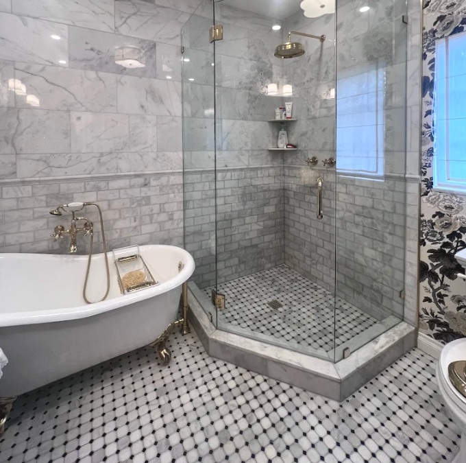Elegant bathroom with marble walls and floors, a glass shower, and a claw-foot tub.