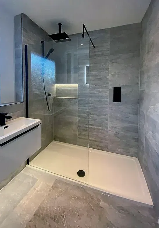 Puerta de ducha de vidrio sin marco instalada en un baño renovado en Miami Beach.