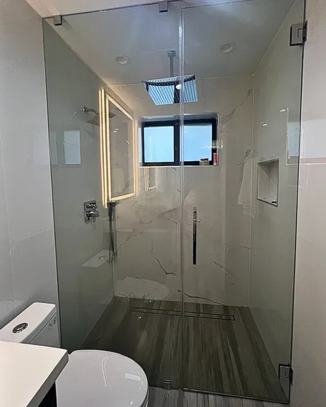Cabina de ducha de vidrio sin marco instalada en un baño moderno en Midtown Miami.