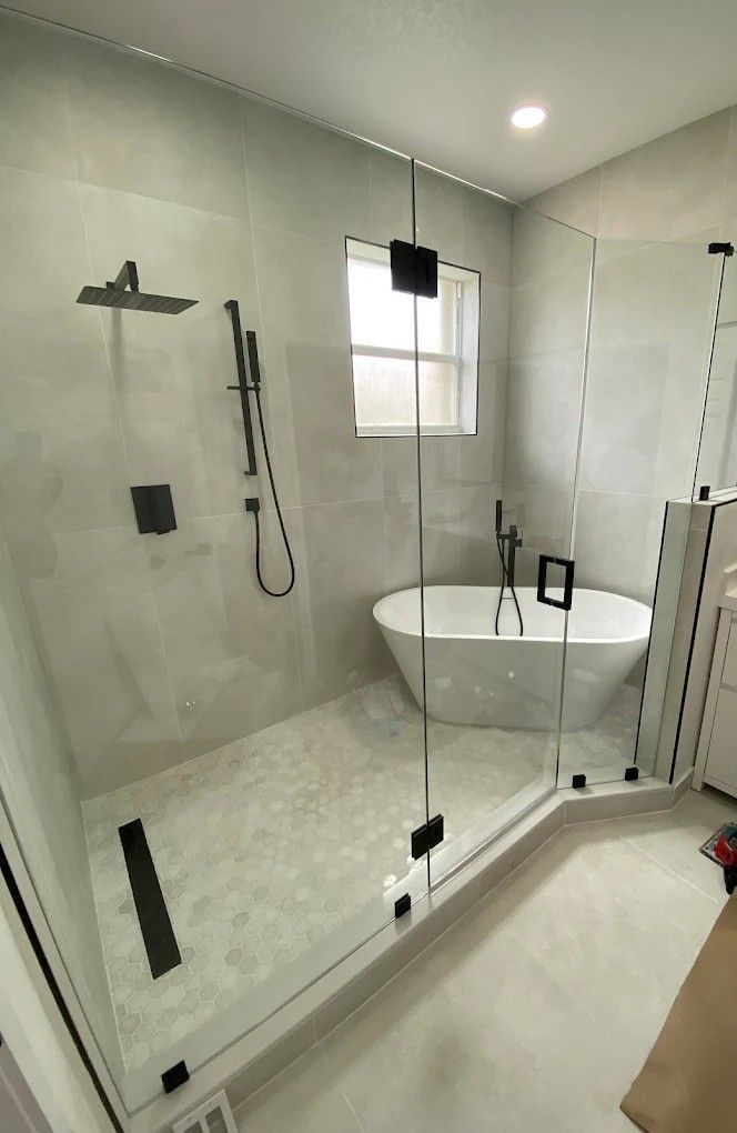 Cabina de ducha de vidrio sin marco con panel angular instalada encerrando a una bañera independiente en Pinecrest.