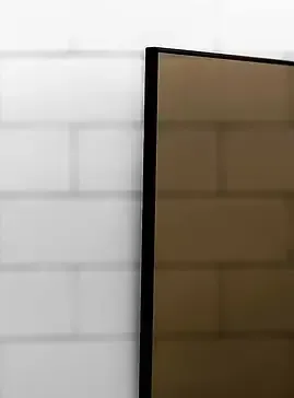 Black-framed mirror reflecting brick wall.