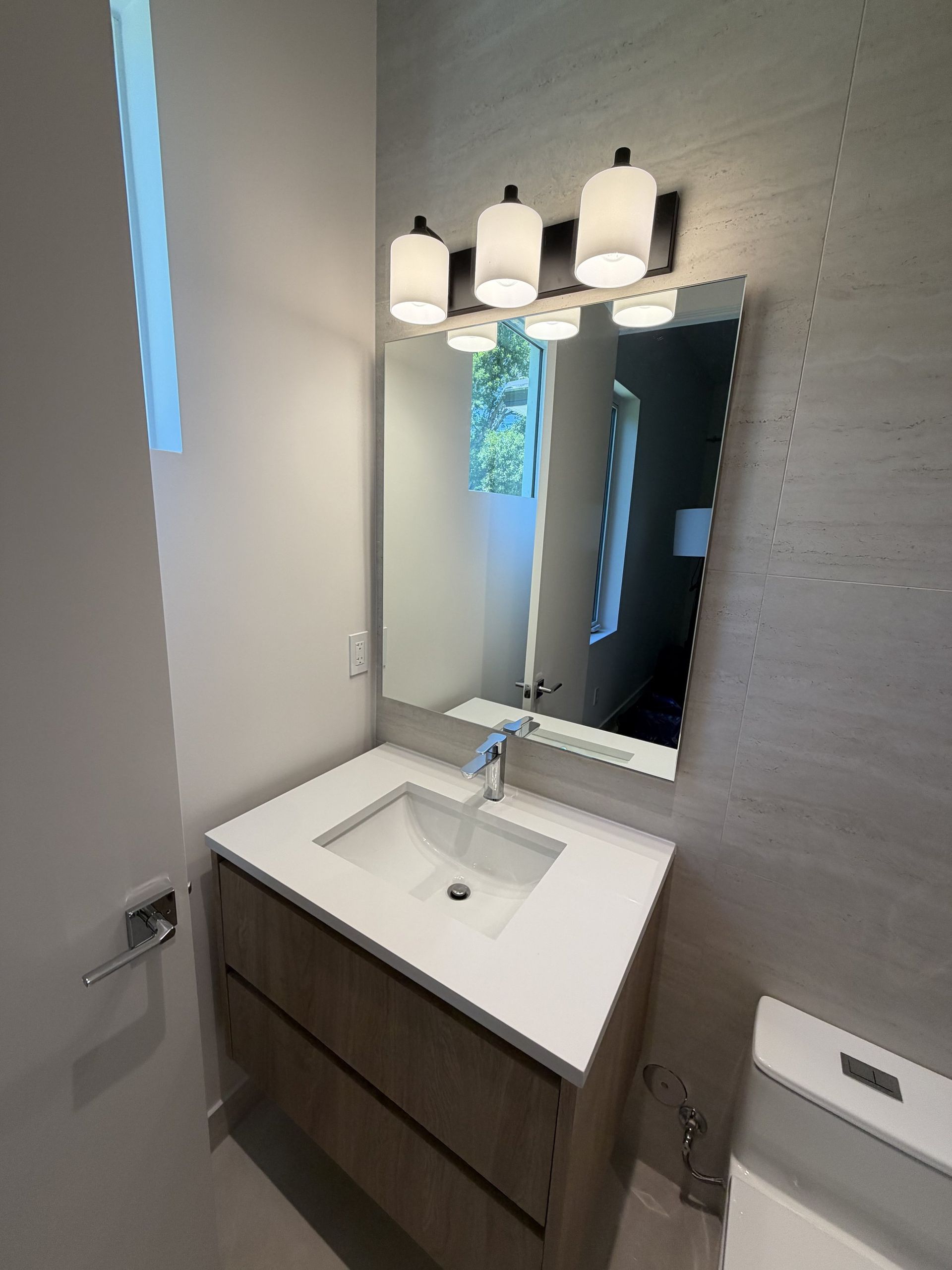 Frameless polished-edge mirror over a modern vanity in a Miami home