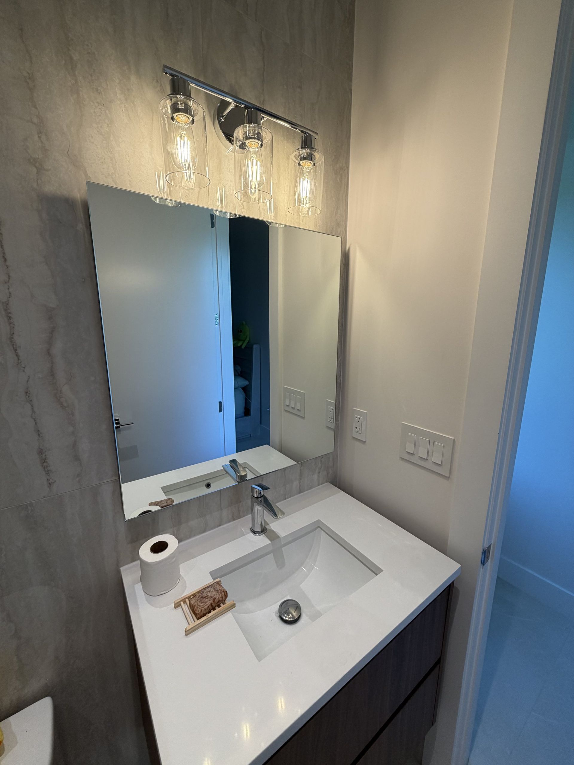 Custom bathroom mirror installed above a vanity with lighting in Miami