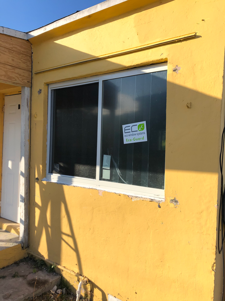 Yellow building exterior with a white-framed window. A door is on the left.