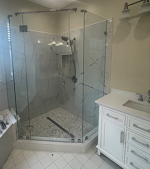 Glass shower enclosure in a bathroom with decorative textured glass. White vanity and tile floors.