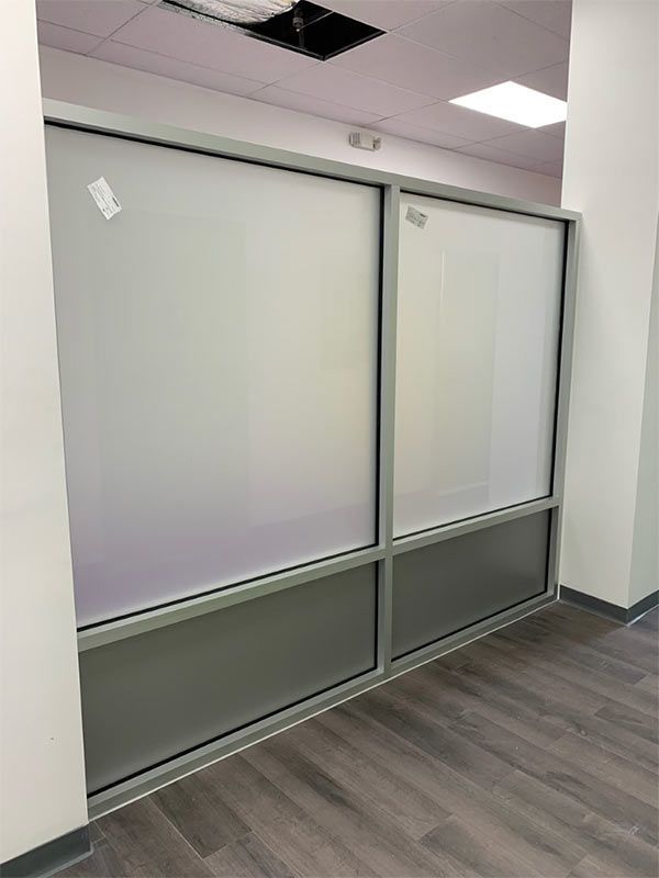 Frosted glass windows in a gray frame. Lower portion is solid gray, top is frosted. Inside hallway, wood floor.