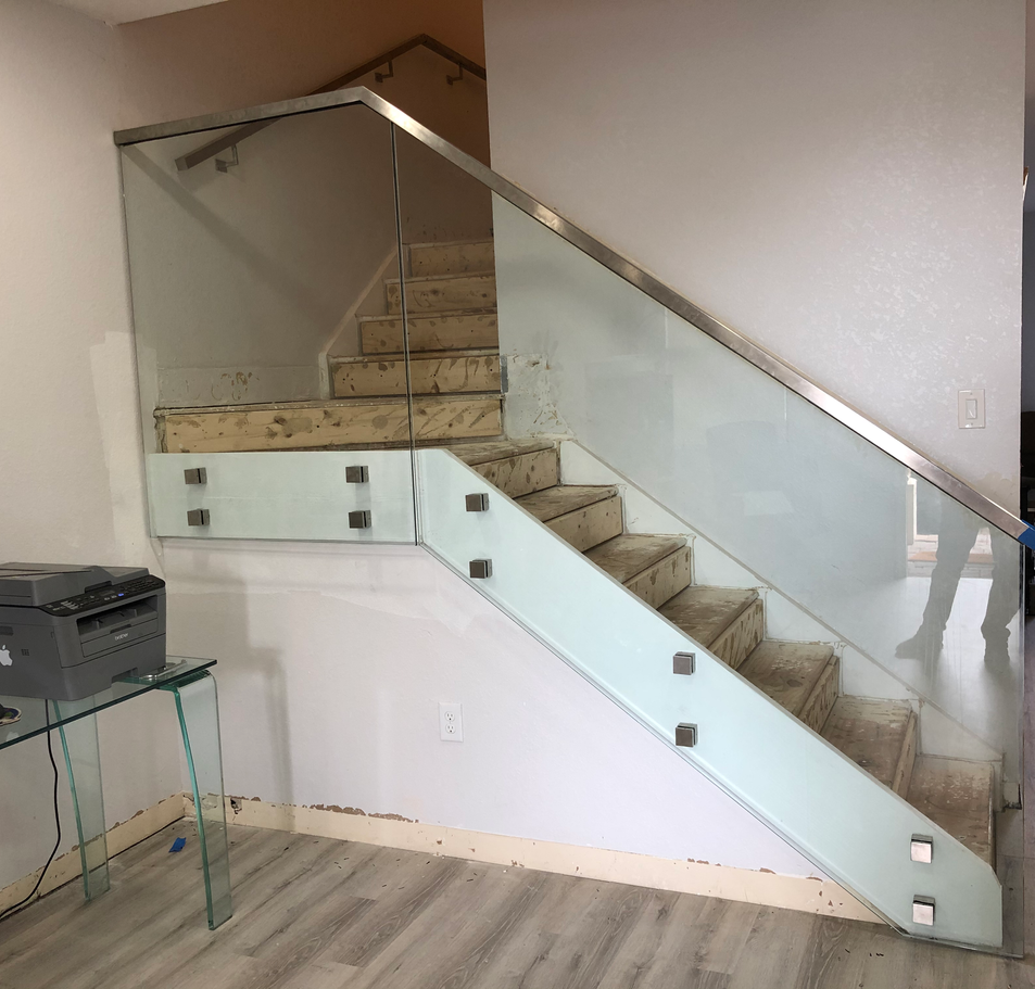 Staircase with glass railing and stainless steel handrail, indoor, modern design.