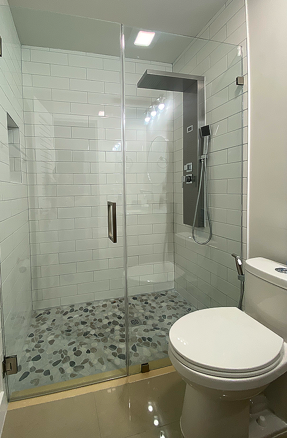 Modern bathroom with a glass shower enclosure, white subway tile, and a toilet.