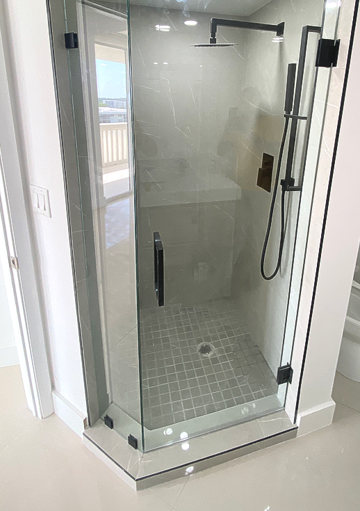 Glass shower with black fixtures and gray tile.