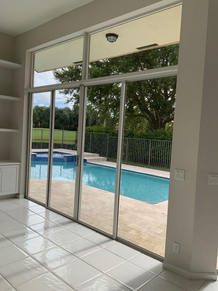 Interior view of a room with large sliding glass doors, pool visible outside.