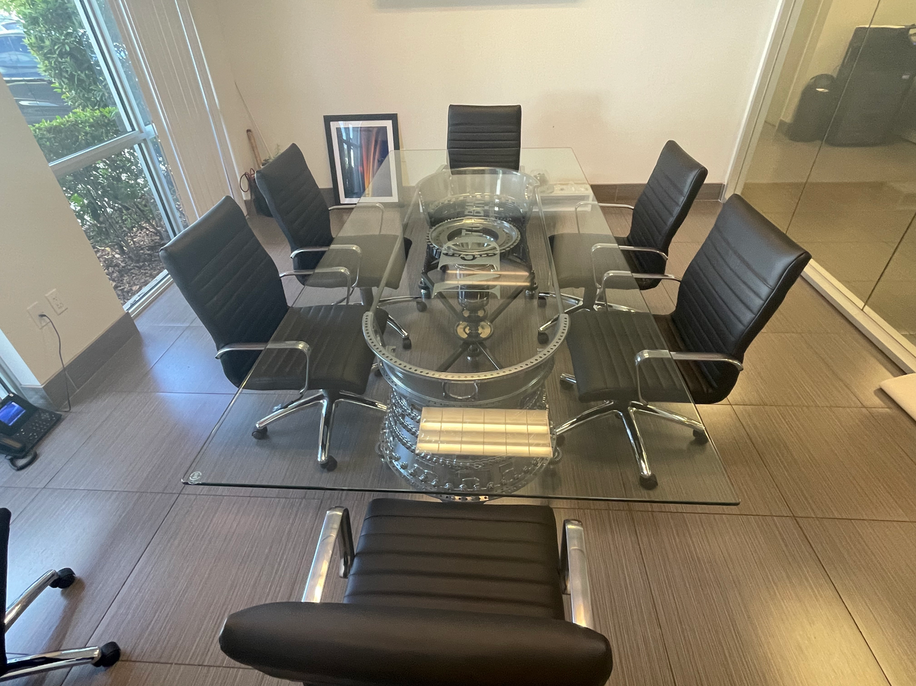 Glass conference table with black chairs in an office setting.