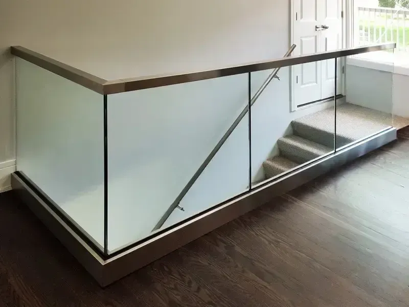 Glass railing and handrail alongside a staircase with frosted glass panels and stainless steel trim.