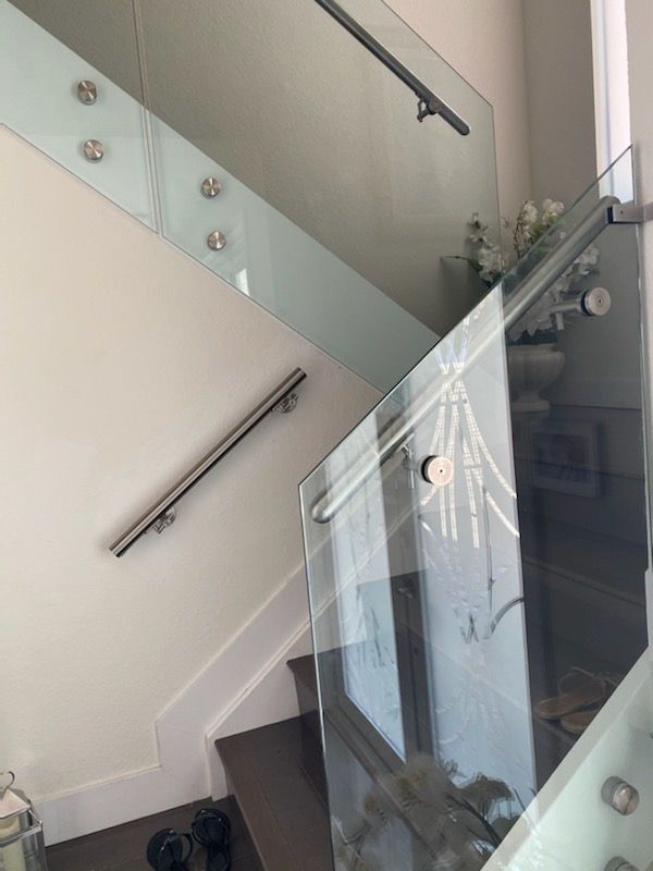 Glass staircase with metal handrails attached to white walls.