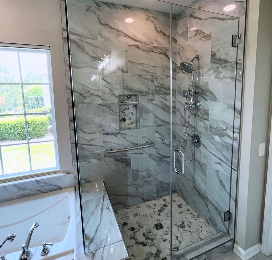 Modern shower with marble-look tile walls, glass door, and a built-in bench.