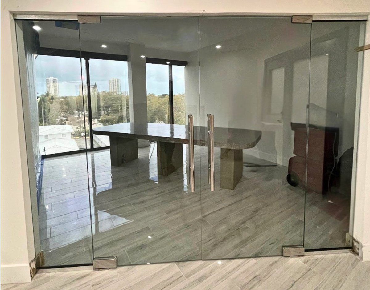 Sala de conferencias de vidrio sin marco con puertas dobles de vidrio y tiradores tipo escalera, con ventanas al fondo, Miami