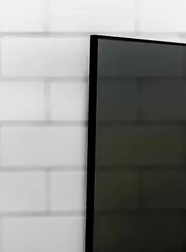 Black television against a white brick wall.