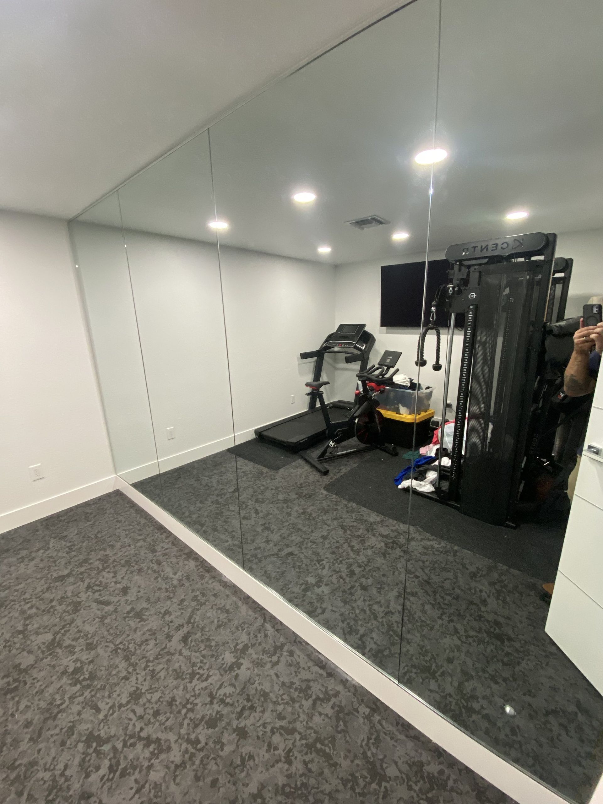 Multi-panel wall-to-wall gym mirror reflecting fitness equipment in a Miami home gym