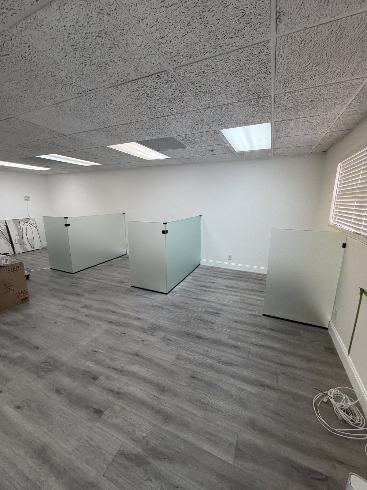 Oficina abierta con una fila de divisores de vidrio a la altura del escritorio fijados al piso, Miami-Dade
