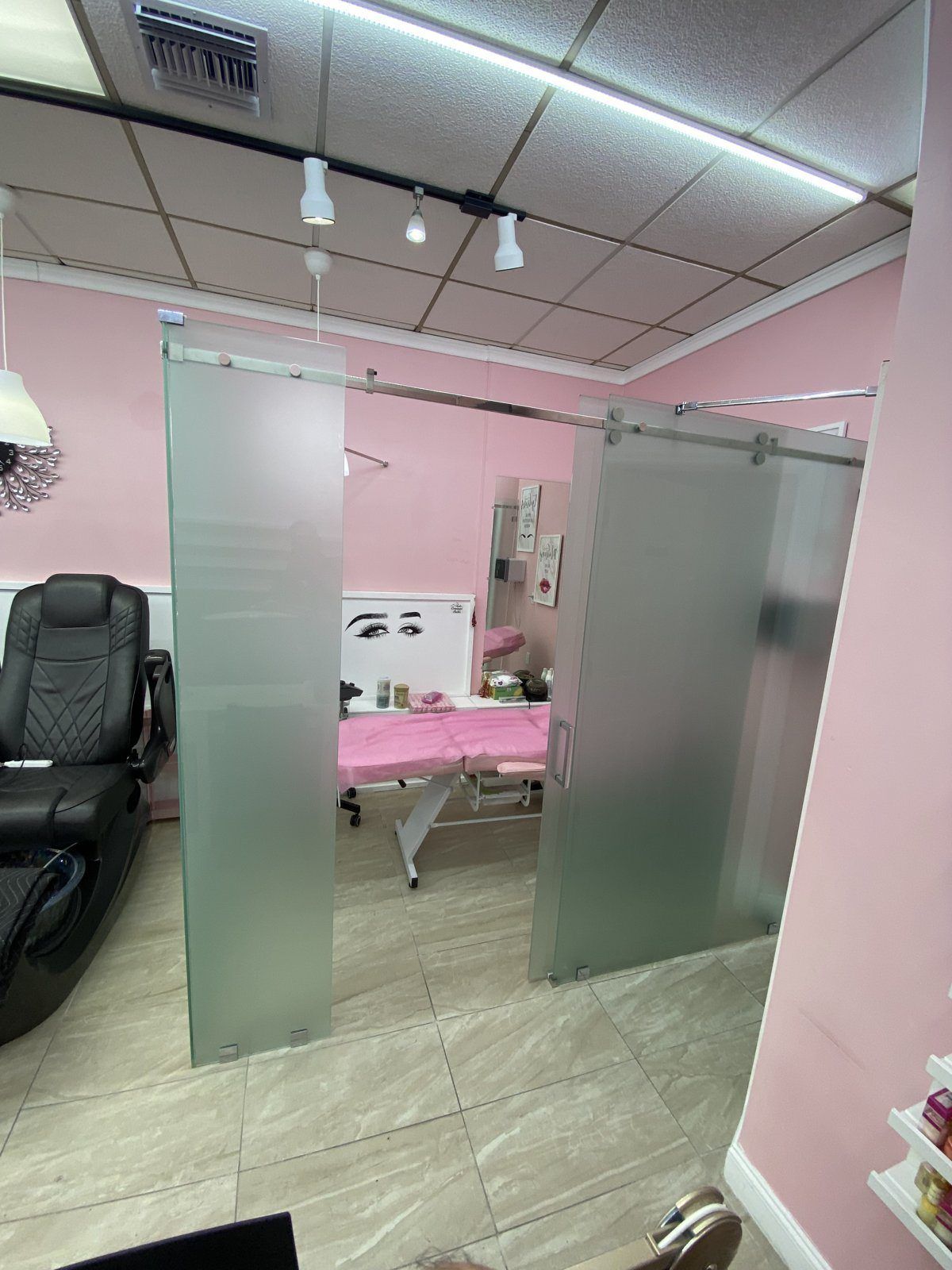 Salón de belleza con paneles de vidrio esmerilado de piso a techo y puerta corrediza de vidrio esmerilado hacia una cabina de tratamiento, Miami