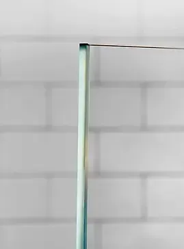 Clear glass shower door corner against white brick wall.