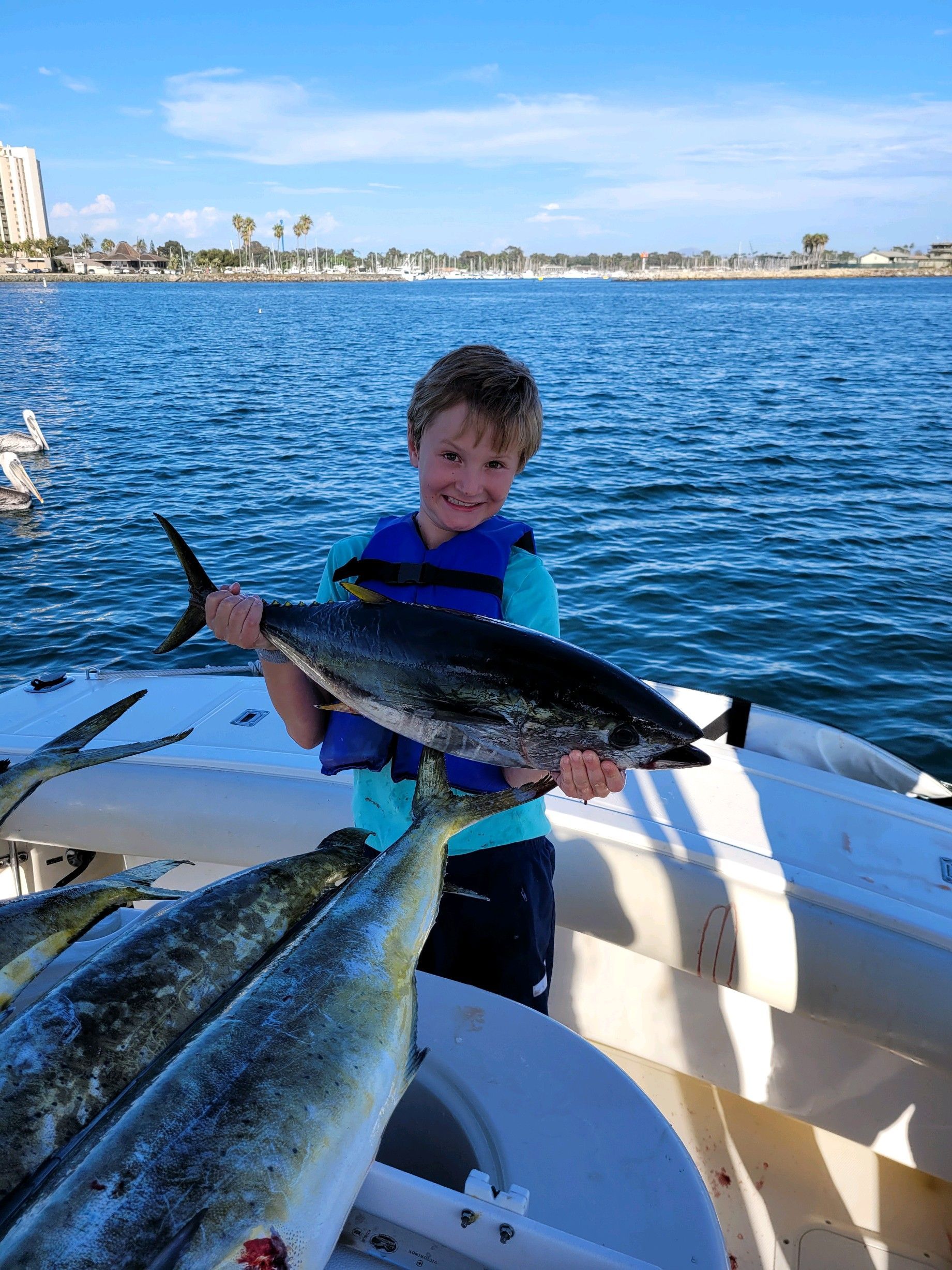 A young boy is holding a large fish on a boat.