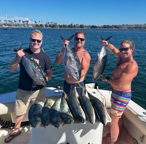 Three men standing on a boat holding fish in their hands