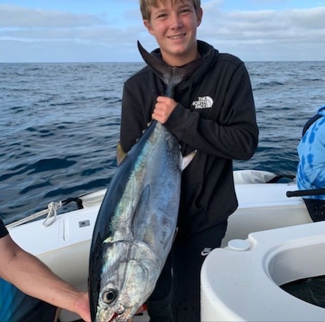 A man wearing a north face sweatshirt is holding a large fish