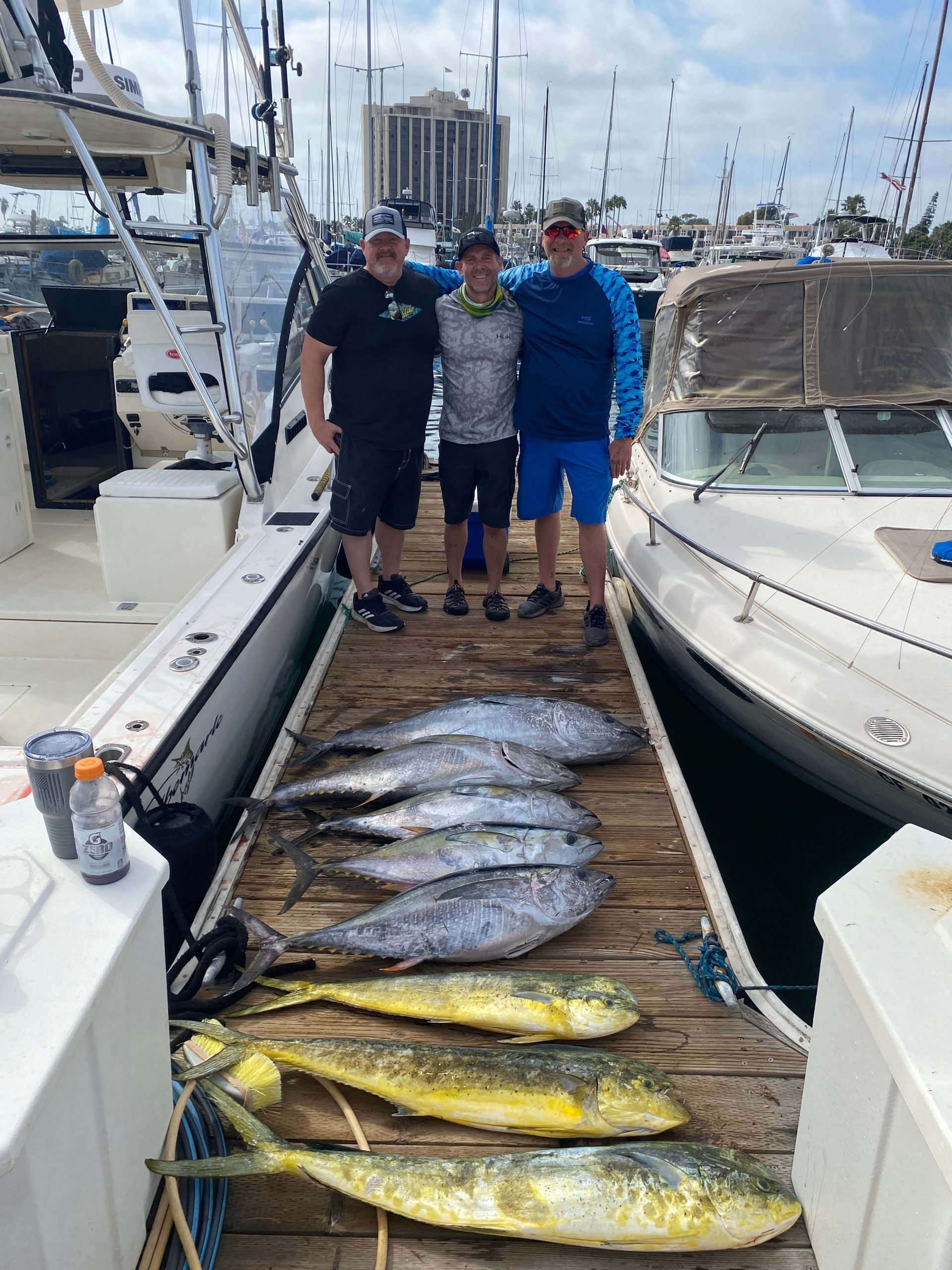 Three men are standing on a dock with a bunch of fish.