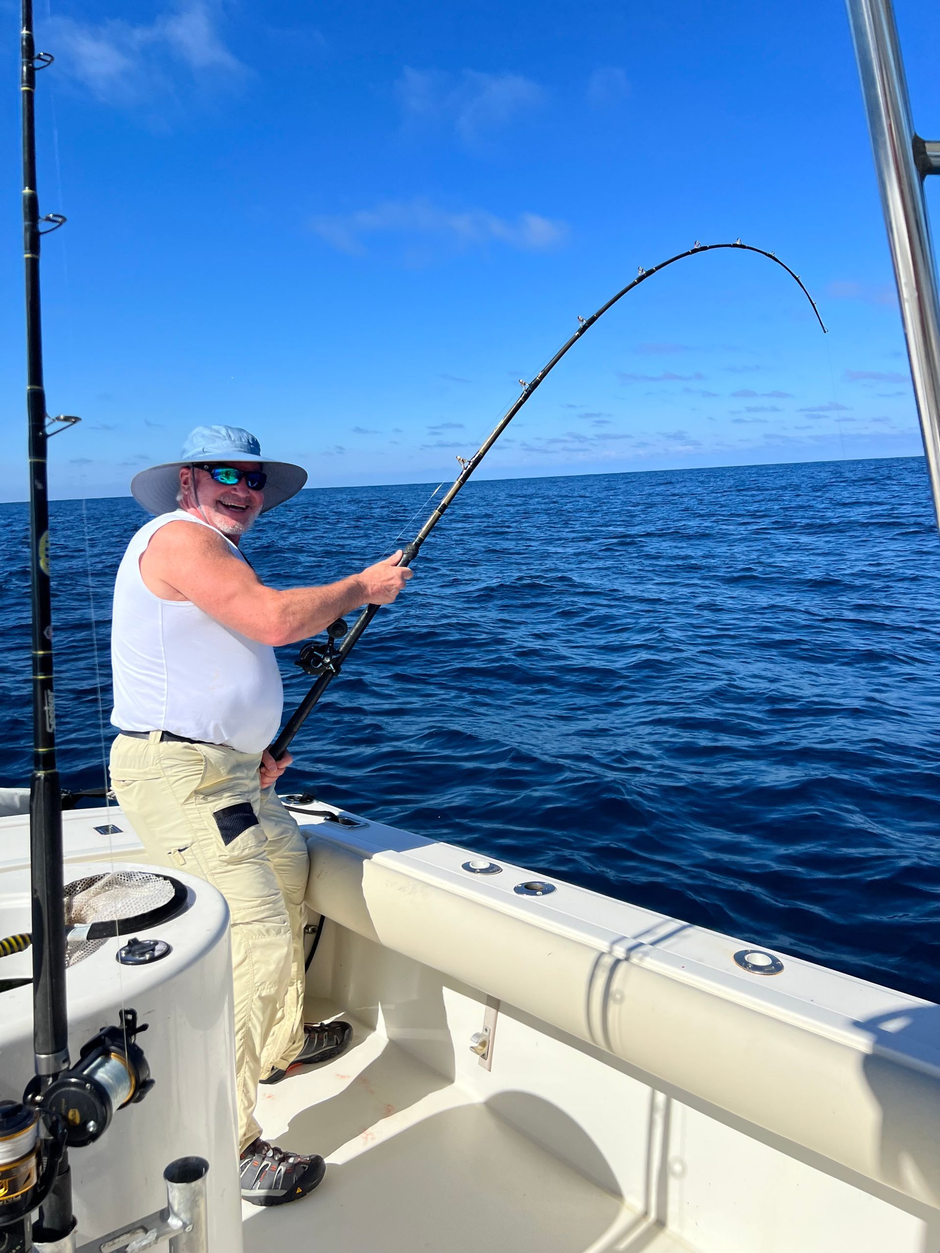 A man is fishing on a boat in the ocean.