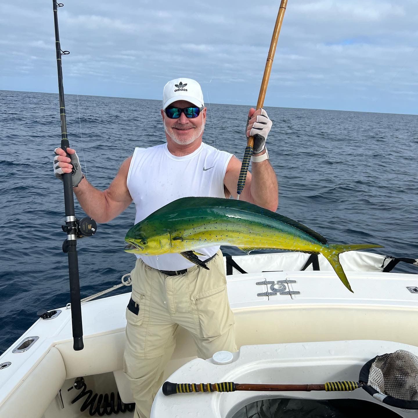 A man is holding a fishing rod and a fish on a boat.