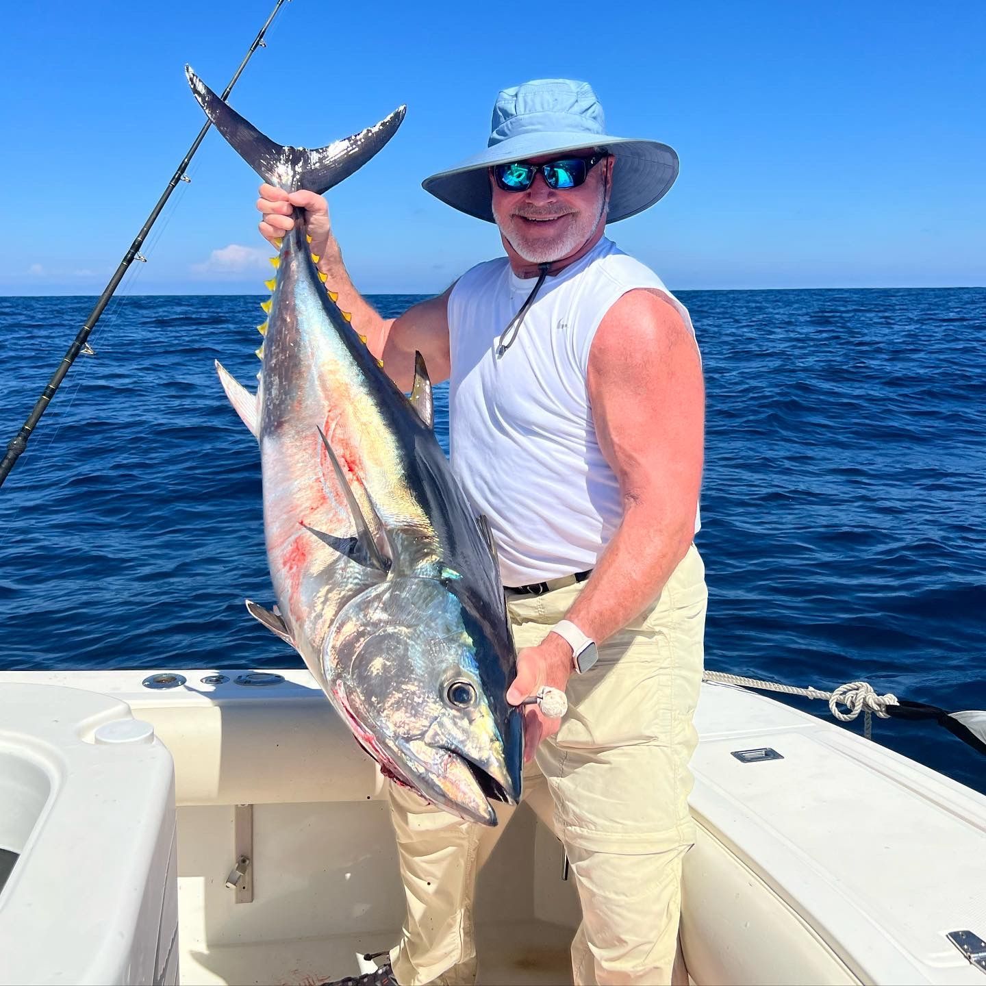 A man is holding a large fish on a boat in the ocean.