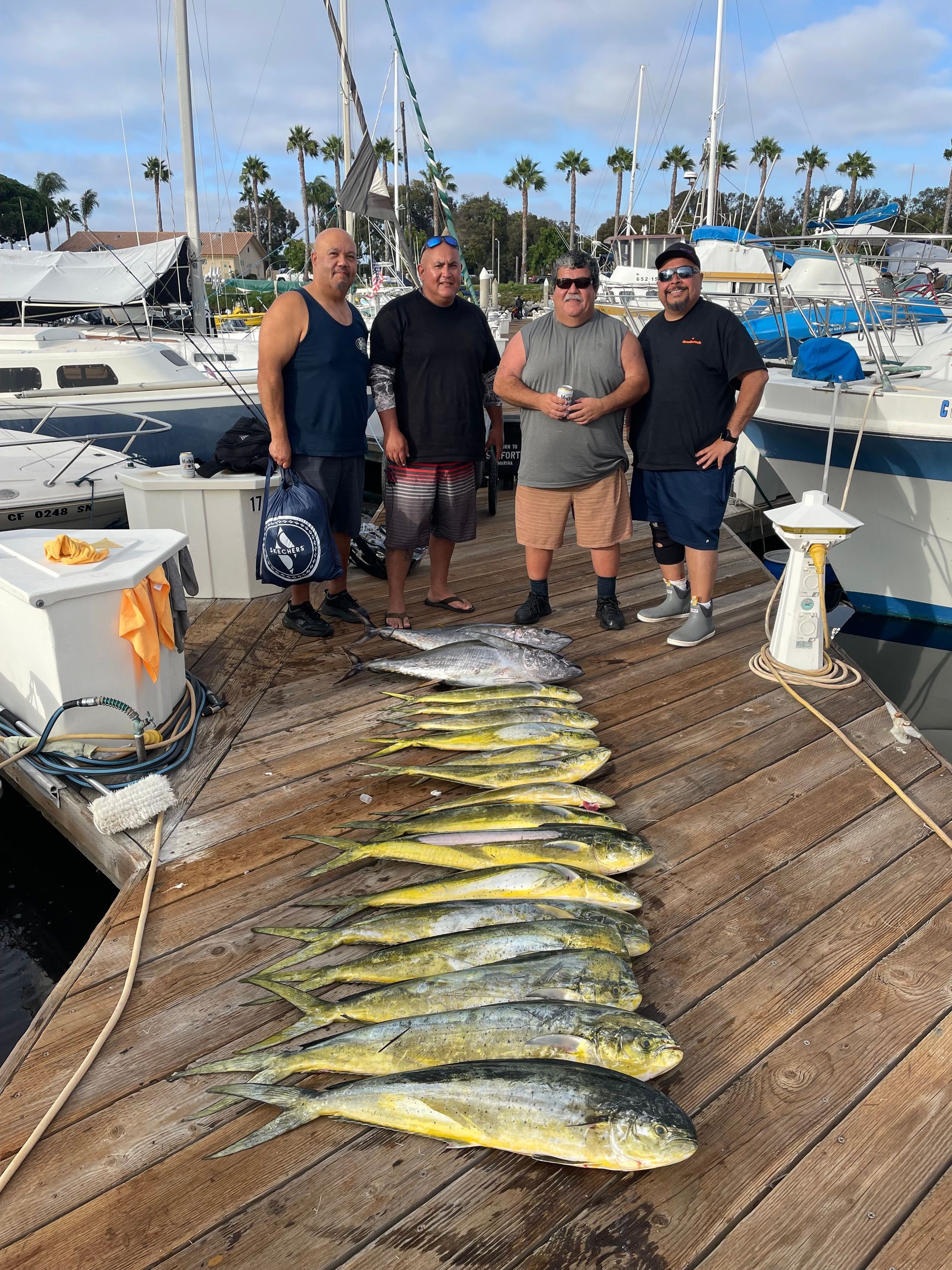 A group of men standing next to a pile of fish on a dock.