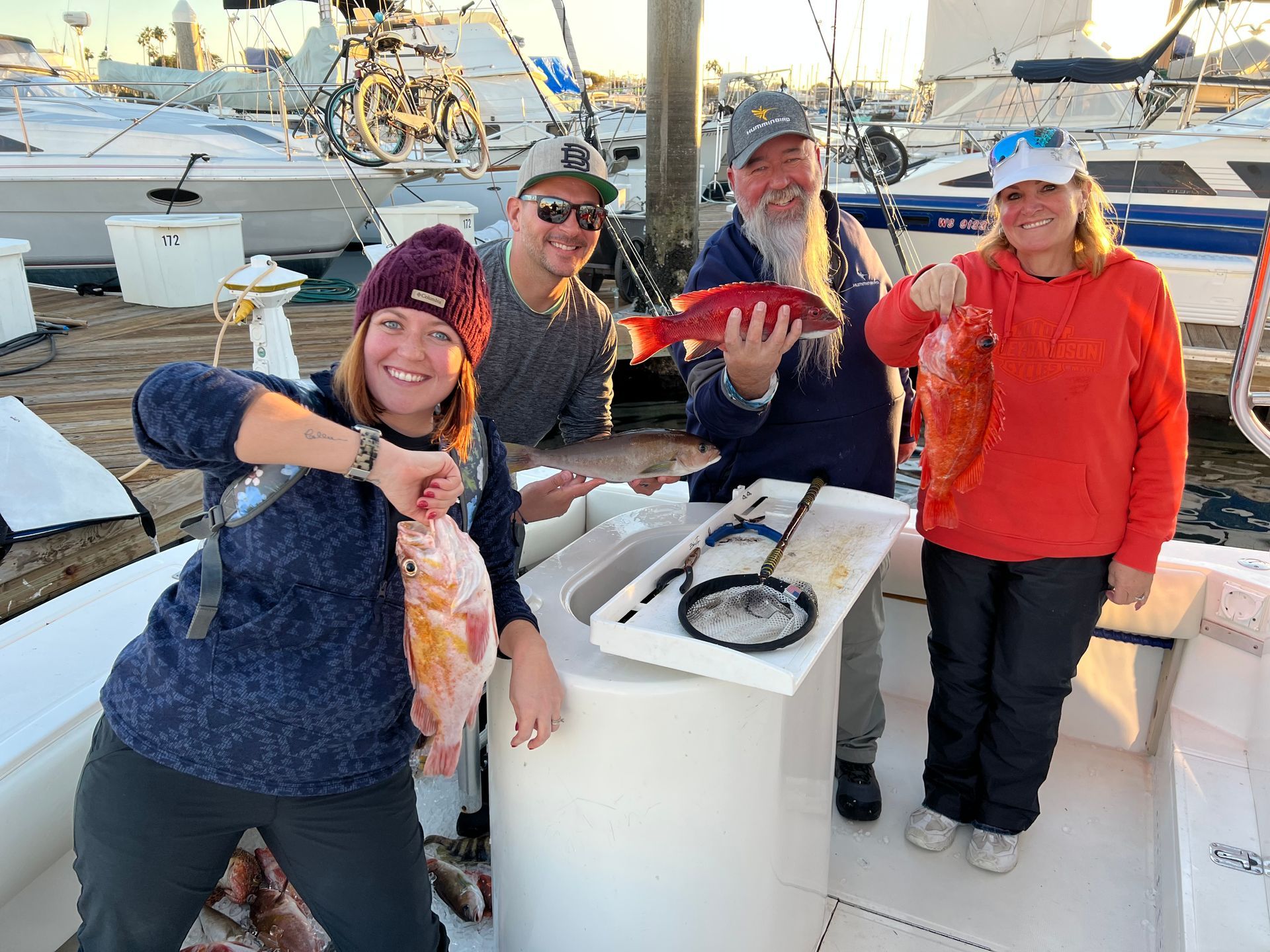 A group of people are standing on a boat holding fish.