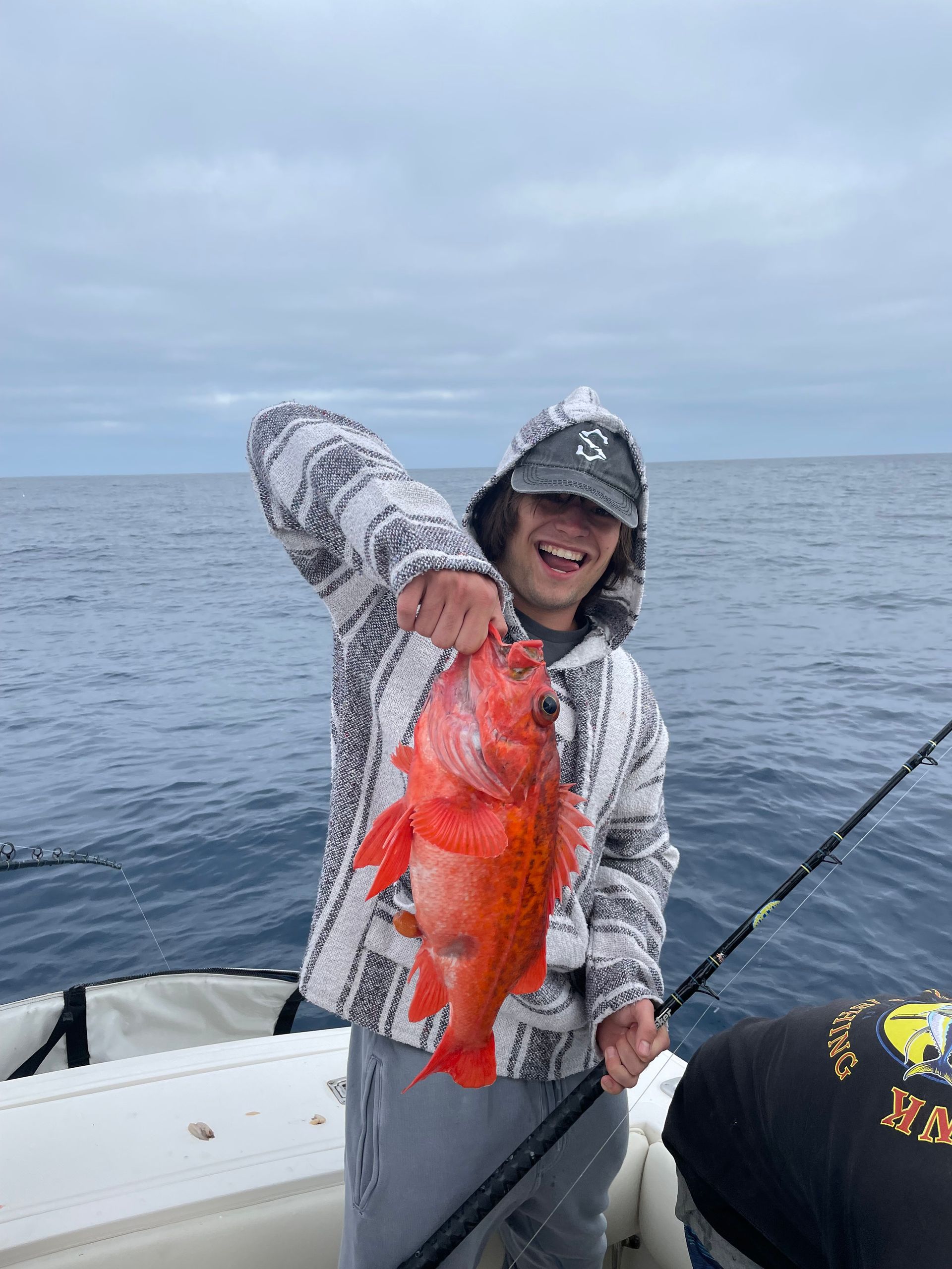 A man is holding a fish on a boat in the ocean.