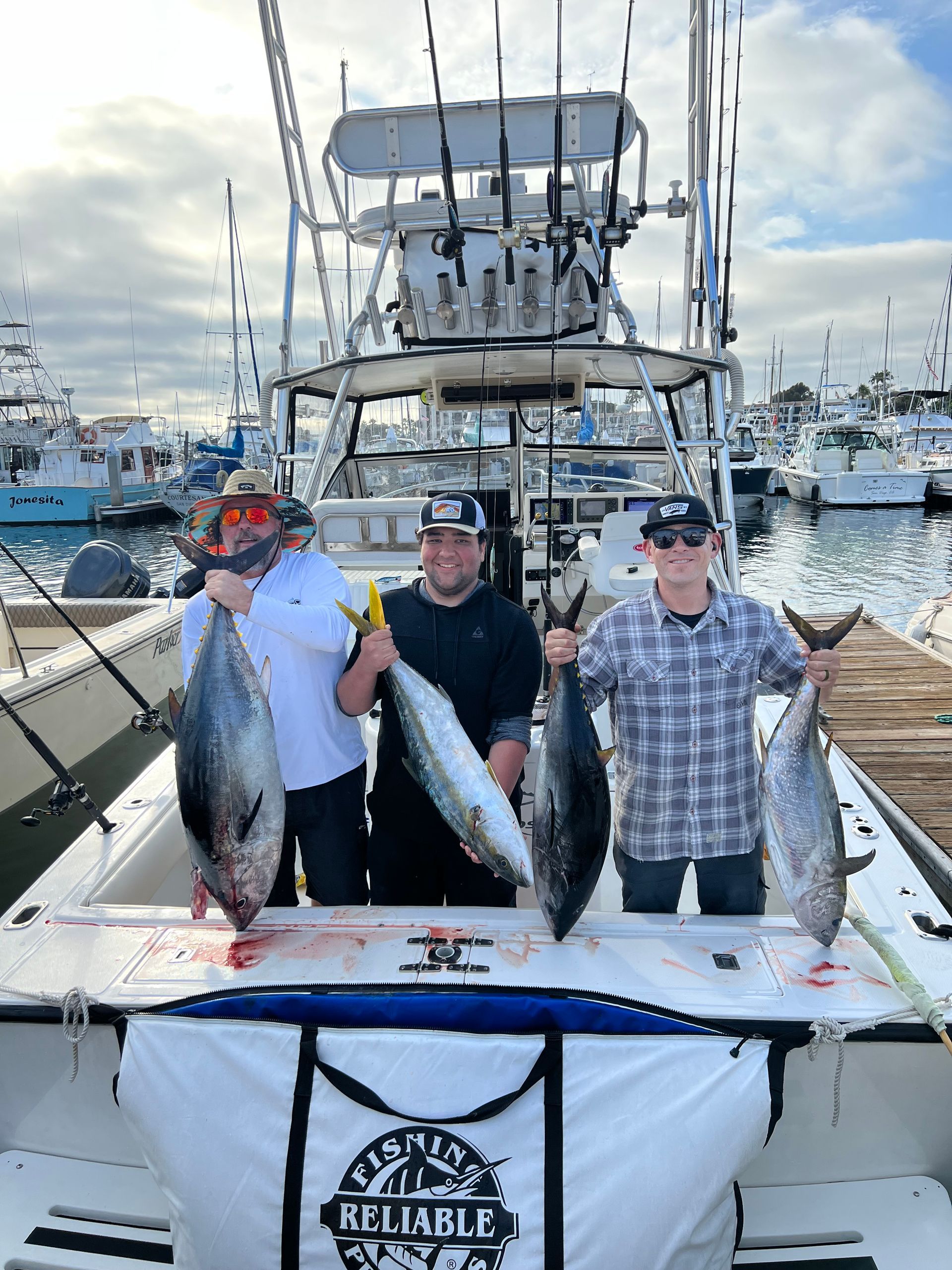Three men are standing on a boat holding fish.