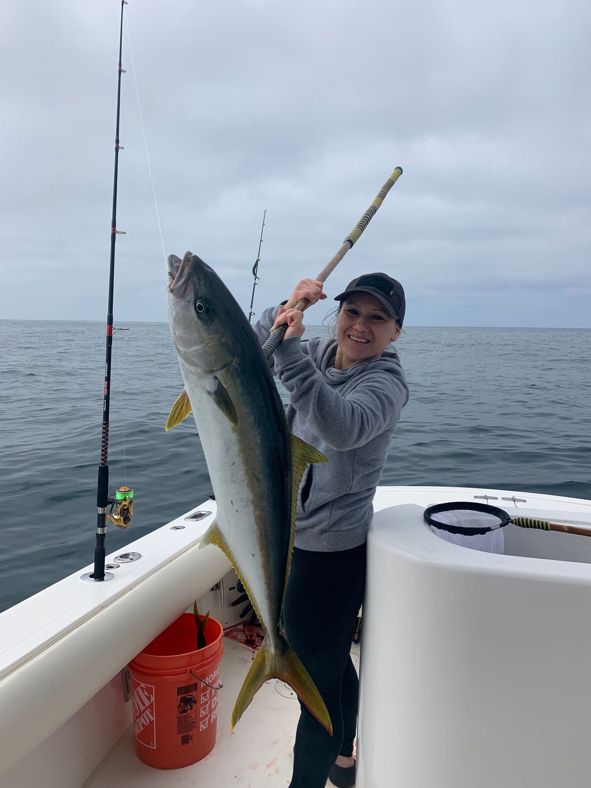 A woman is holding a large fish on a boat.