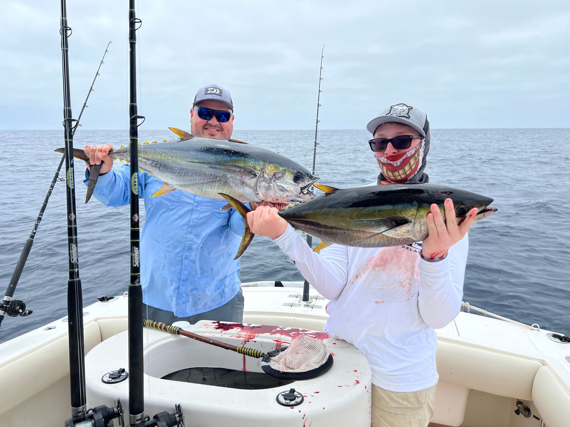 Two men are holding two fish on a boat in the ocean.