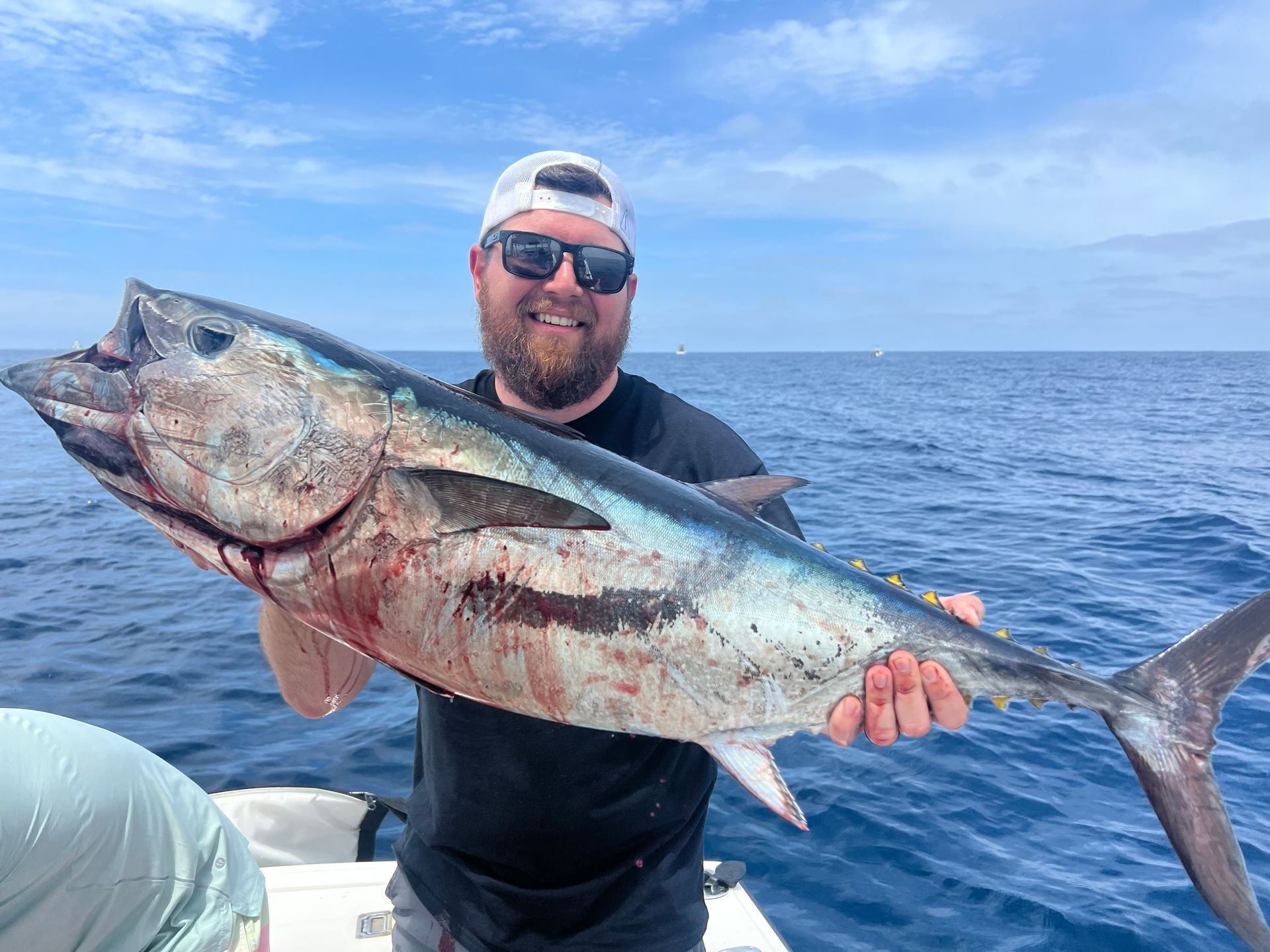 A man is holding a large fish on a boat in the ocean.