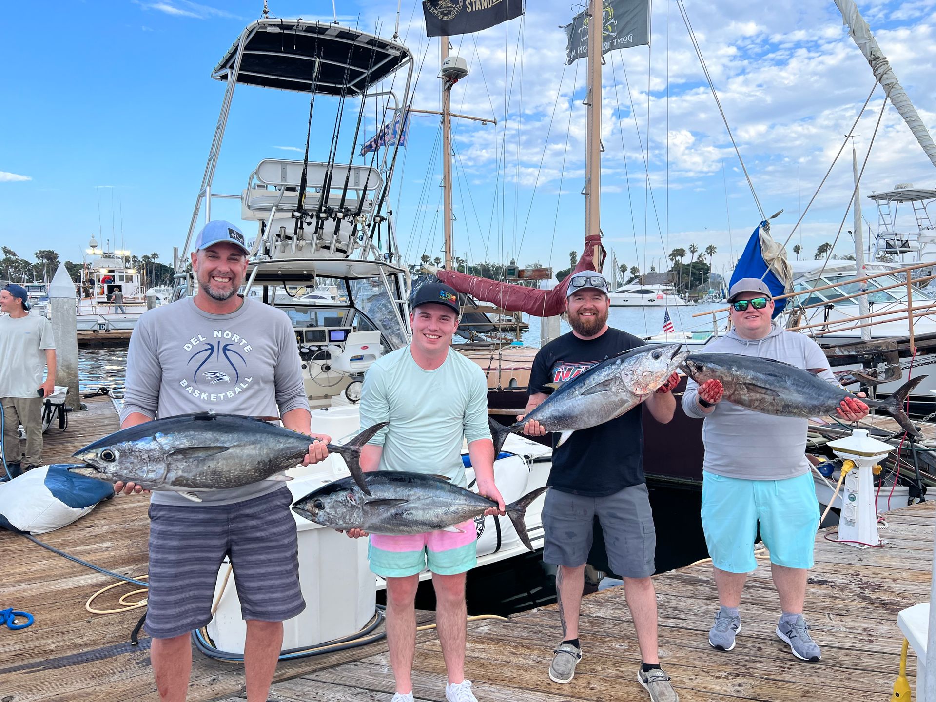 A group of people are standing next to each other holding fish in front of a boat.