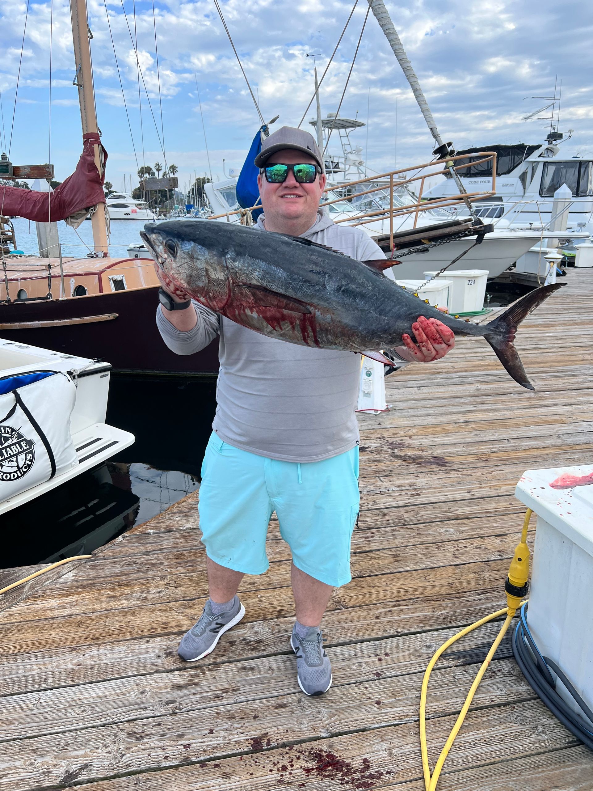 A man is holding a large fish on a dock.