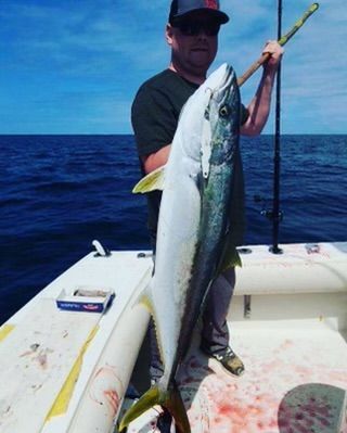 A man is holding a large fish on a boat