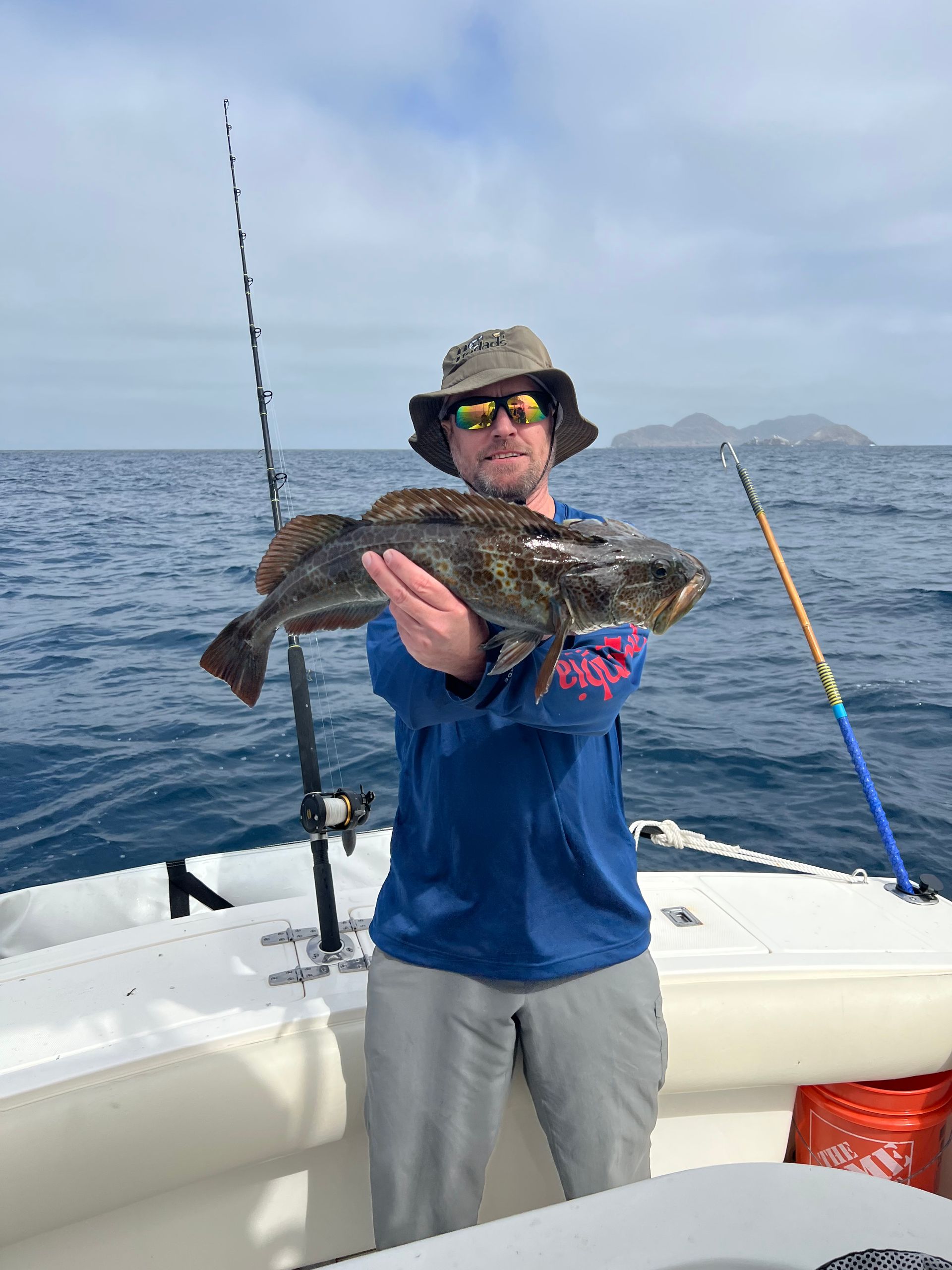 A man is holding a fish on a boat in the ocean.