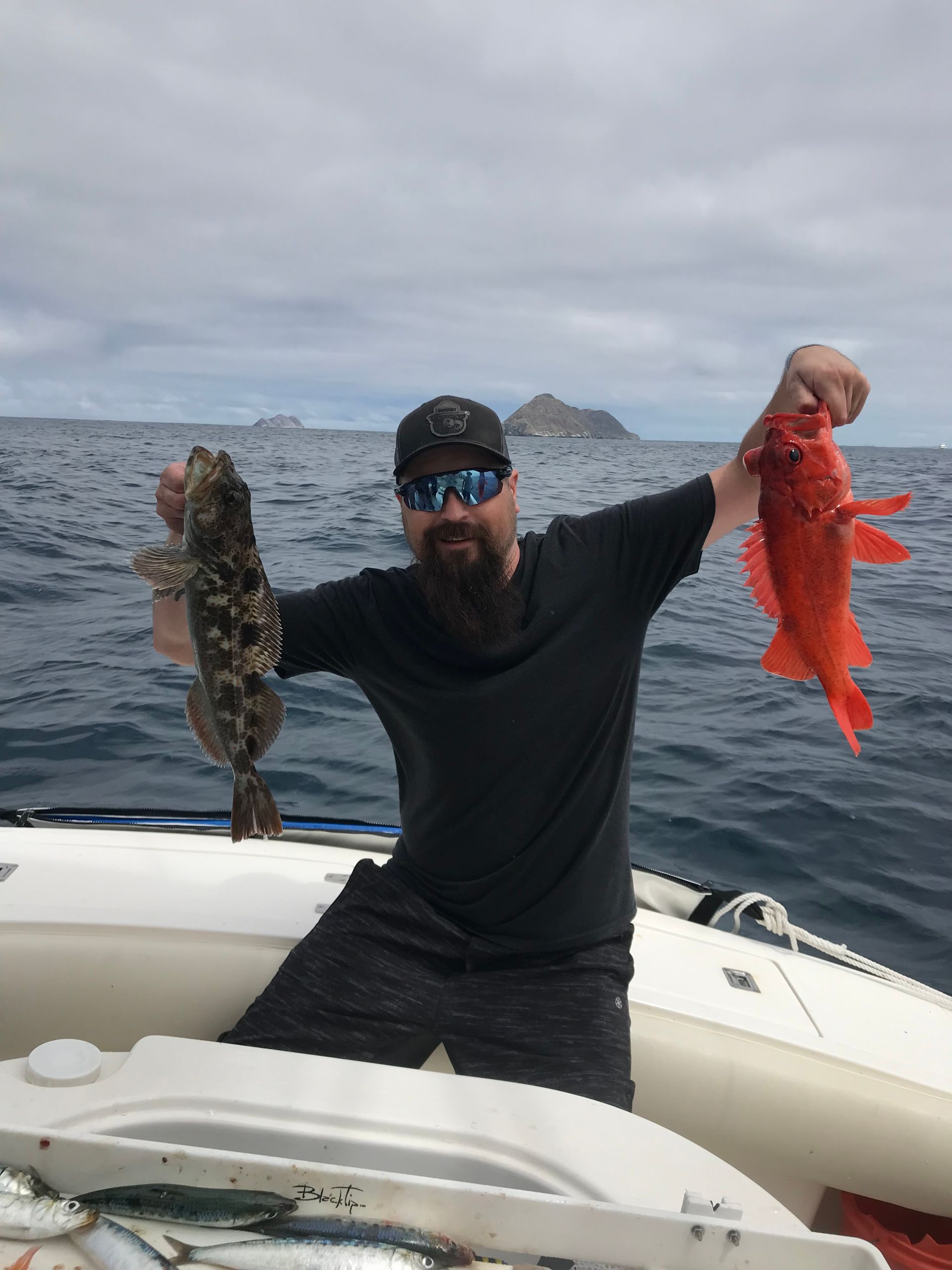 A man on a boat holding two fish in his hands