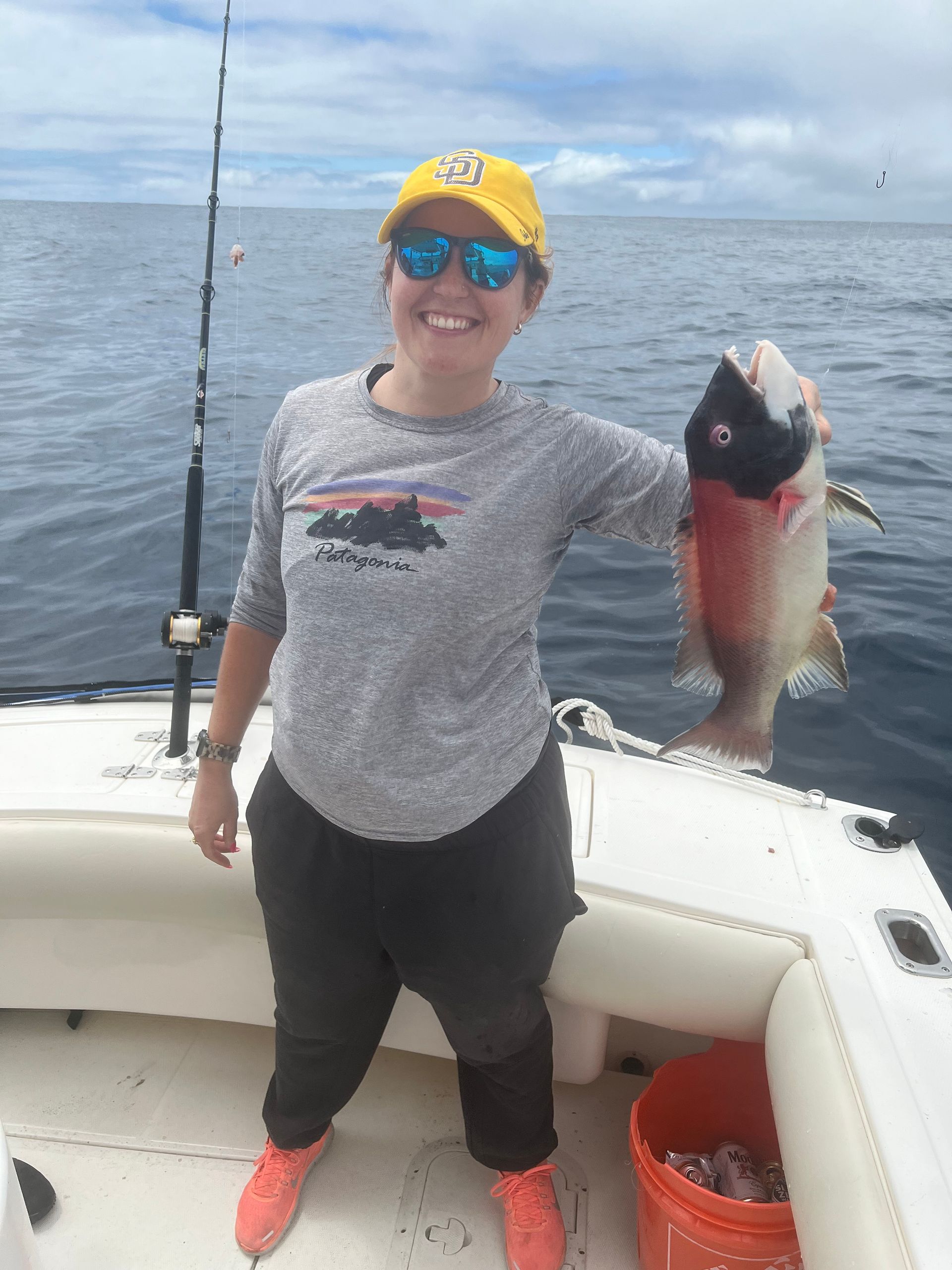 A woman is holding a large fish on a boat